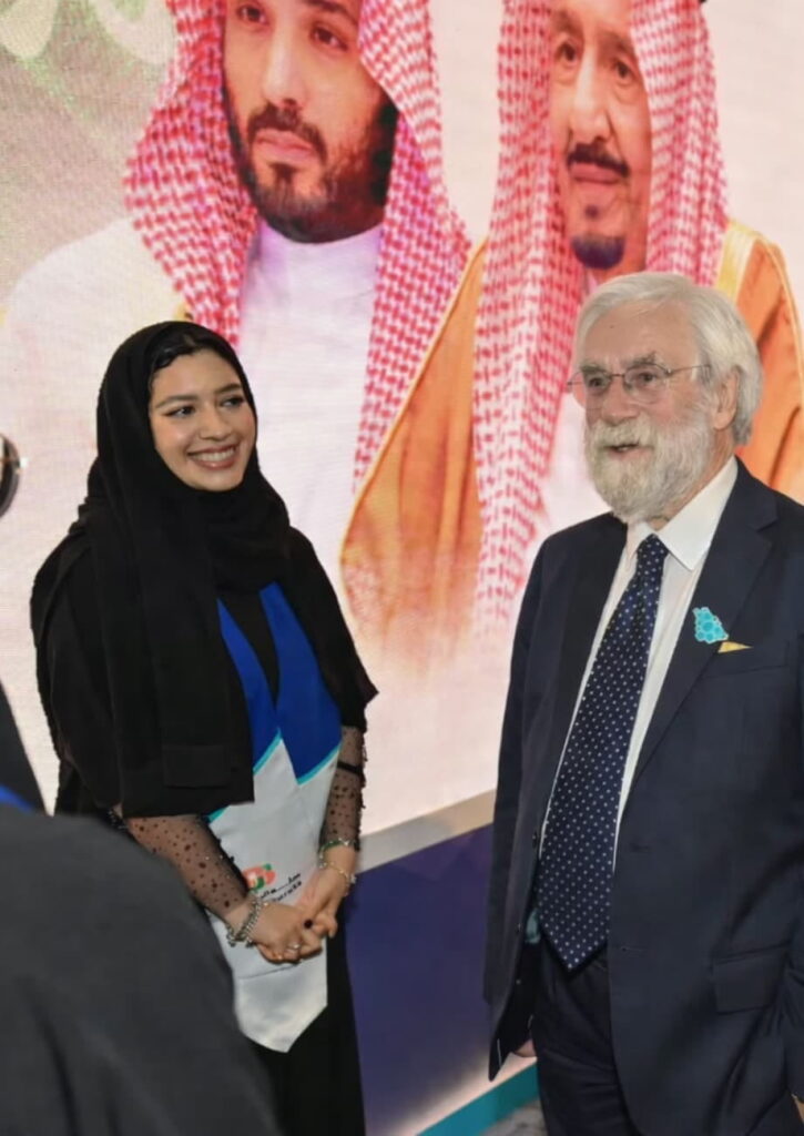 Roy speaking with a client at an event while a woman stands beside him.