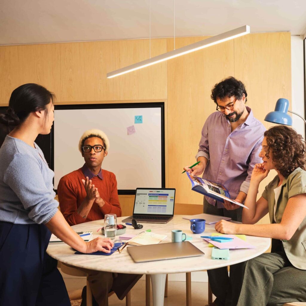 Team discussing ideas around a table during a collaborative office meeting.