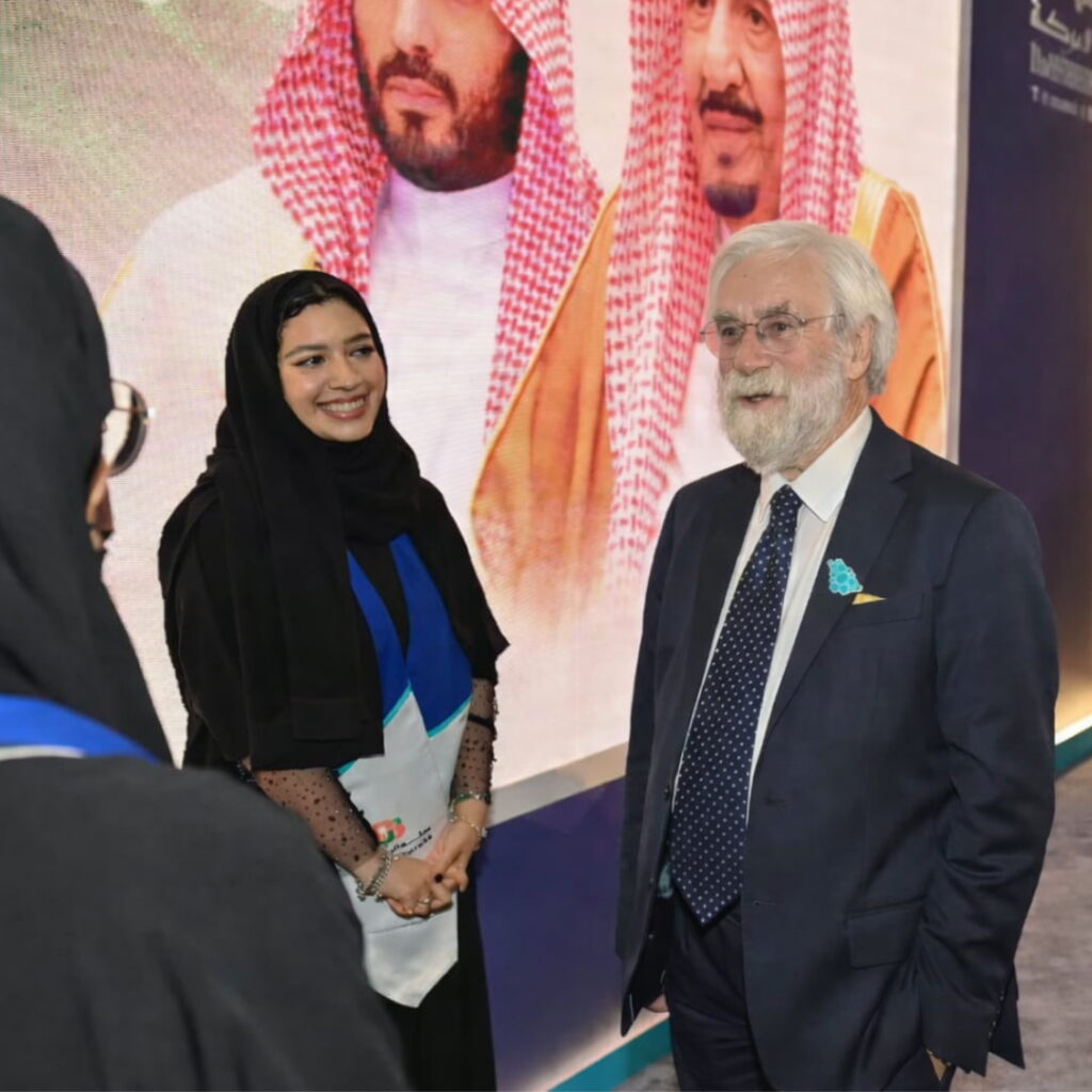 Roy speaking with a client at an event while a woman stands beside him.