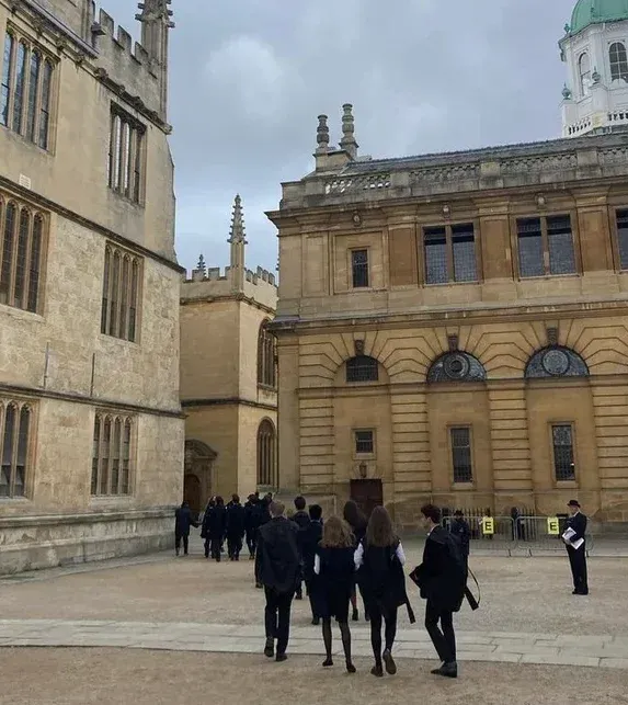 People walking through a historic university courtyard, representing education, learning, and academic thinking.